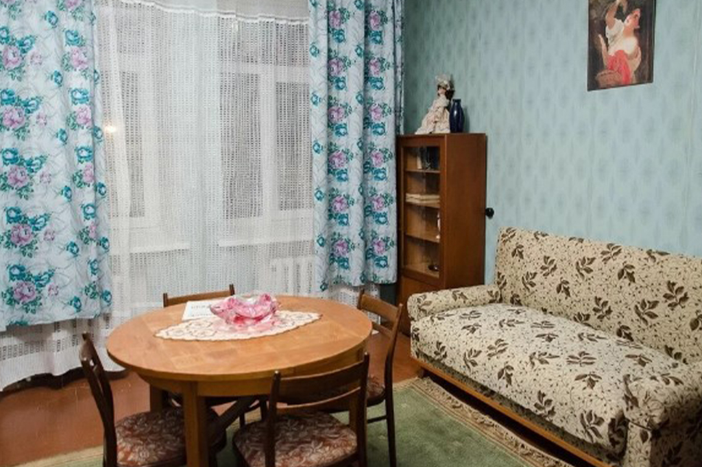Класичний інтер’єр радянських часів: круглий обідній стіл, шафа з посудом і диван з квітковим принтом