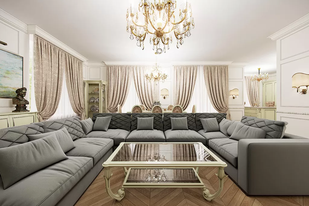 Розкішна класична вітальня з великим кутовим диваном у сірому кольорі, декоративними подушками та кришталевими люстрами.