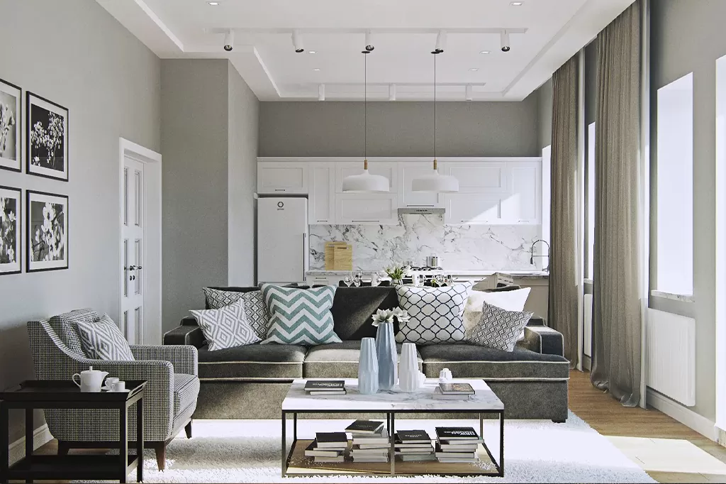 Простора кімната-студія з темно-сірим диваном у мінімалістичному стилі, світлими стінами та білою кухнею з мармуровим фартухом